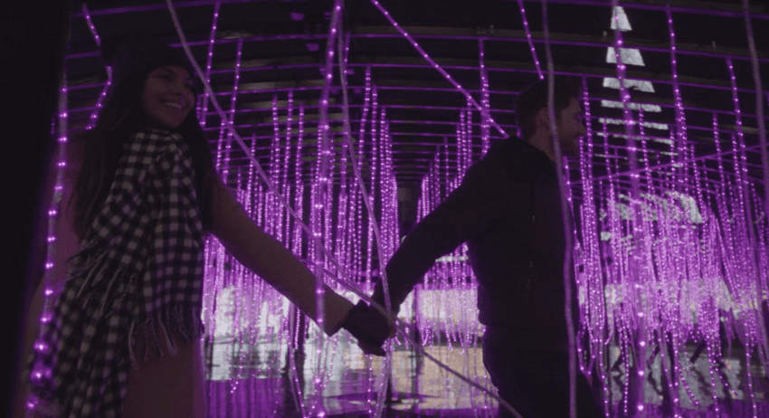 couple walking through dangling purple lights